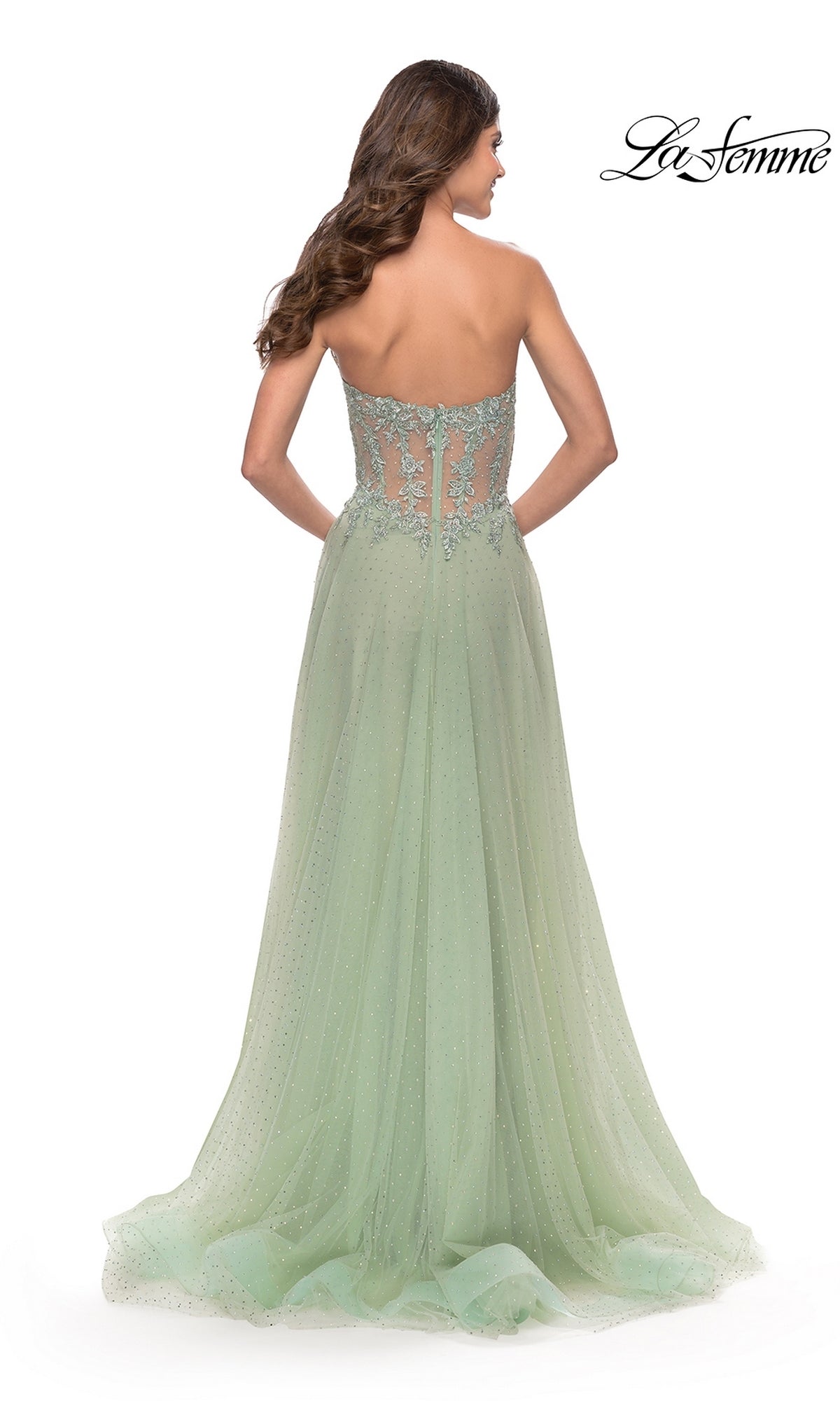 A woman wears the La Femme Strapless Sheer-Waist Prom Dress 31367 in light green, featuring lace embroidery on the sheer back and an elegant A-line tulle skirt. The La Femme logo appears in the top right corner.